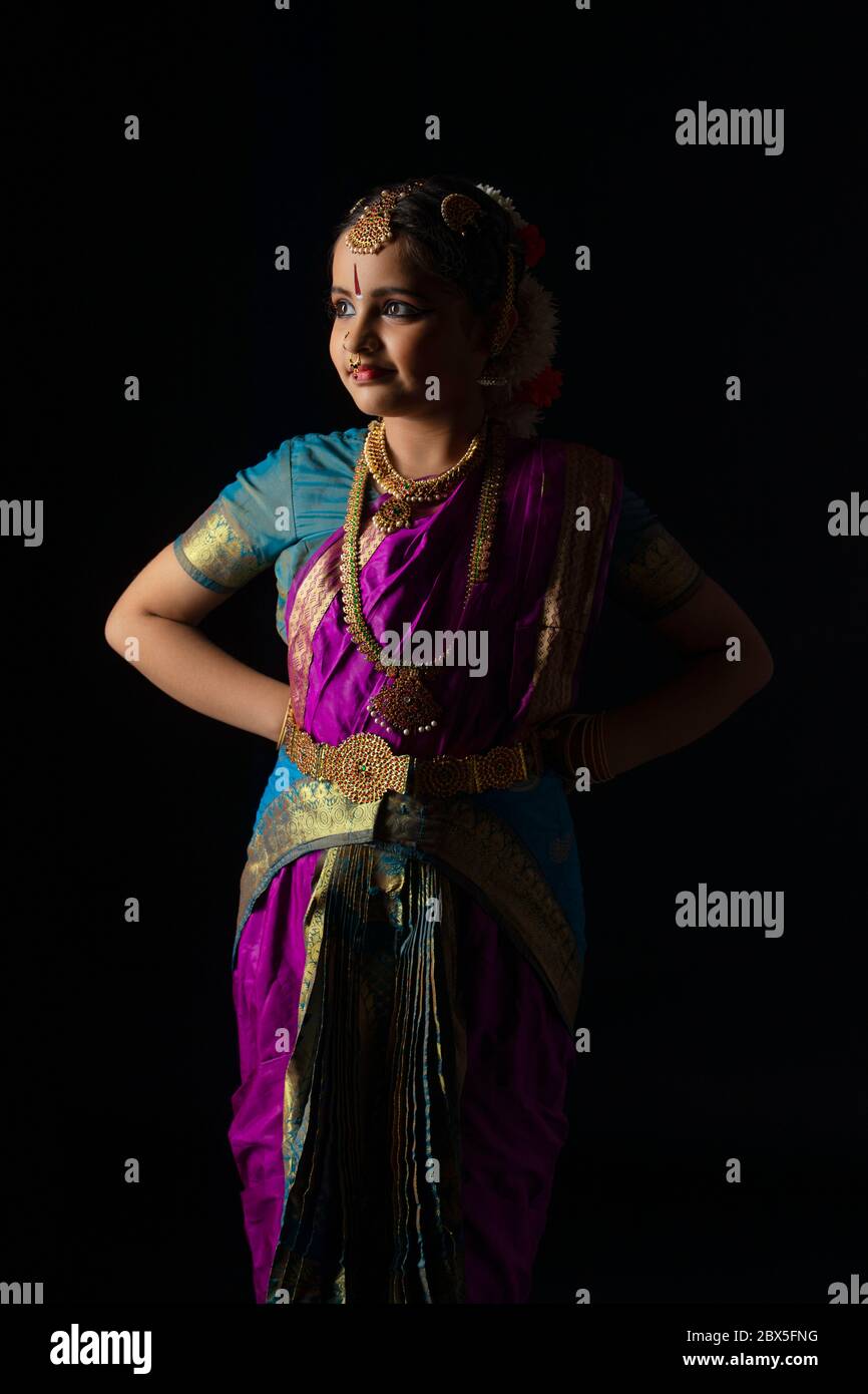 Giovane ballerina bharatnatyam in piedi davanti ad uno sfondo nero. Foto Stock