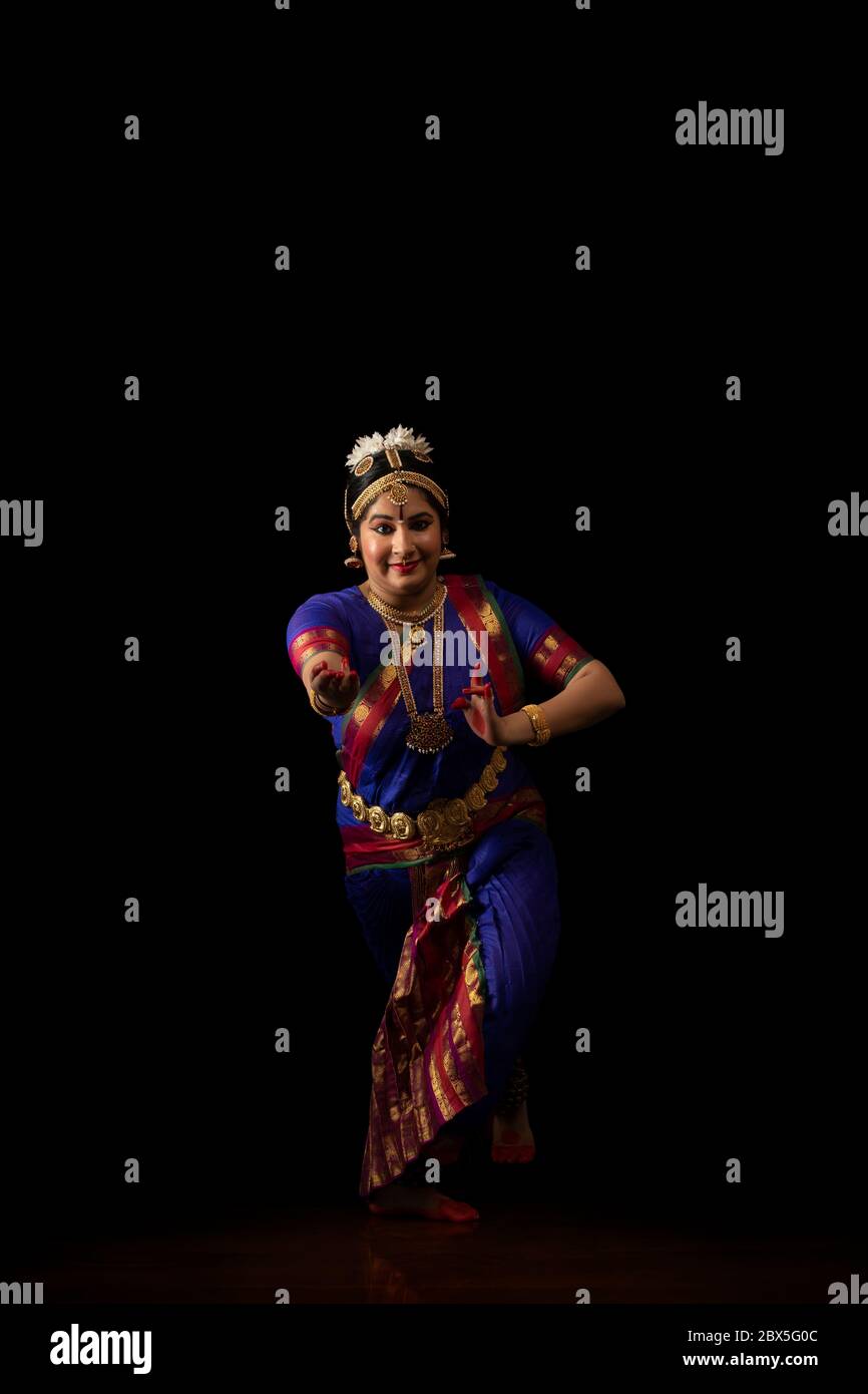Ballerina Bharatnatyam che si esibisce di fronte a uno sfondo scuro. Foto Stock