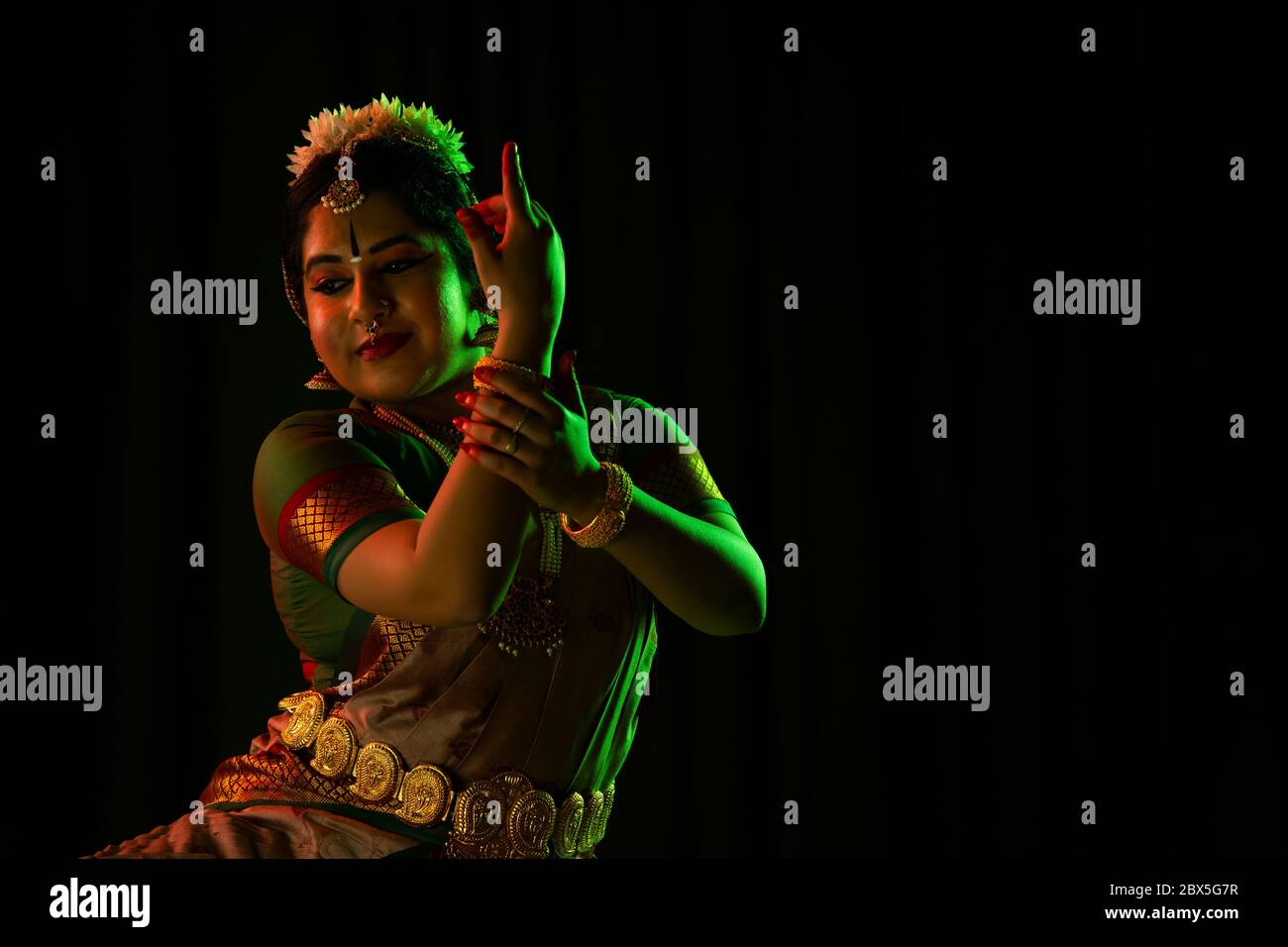 Ballerina Bharatnatyam che dà una graziosa esecuzione di fronte a uno sfondo scuro. Foto Stock