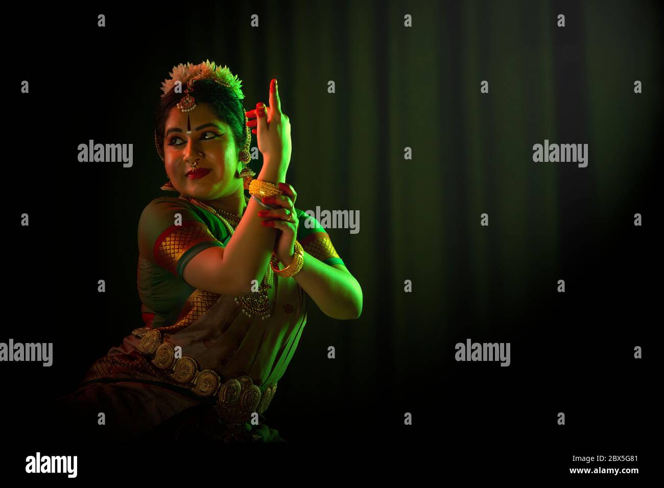 Ballerina Bharatnatyam che offre una performance affascinante davanti a uno sfondo scuro. Foto Stock
