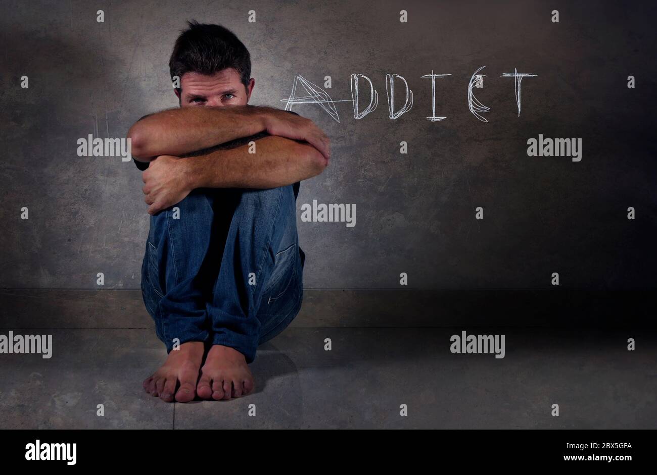 giovane depresso addict uomo seduto isolato sul pavimento in ombra drammatico studio sfondo triste e frustrato sofferenza depressione in gioco di droga inte Foto Stock