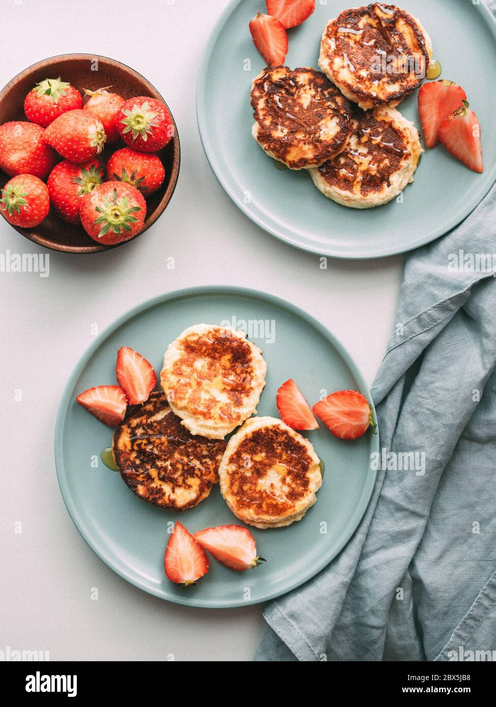 Frittelle dolci al formaggio servite sul piatto fragole. Frittelle di formaggio di cottage, scirniki, frittelle di ricotta, frittelle di cagliata. Vista dall'alto o in piano. Verticale. Foto Stock