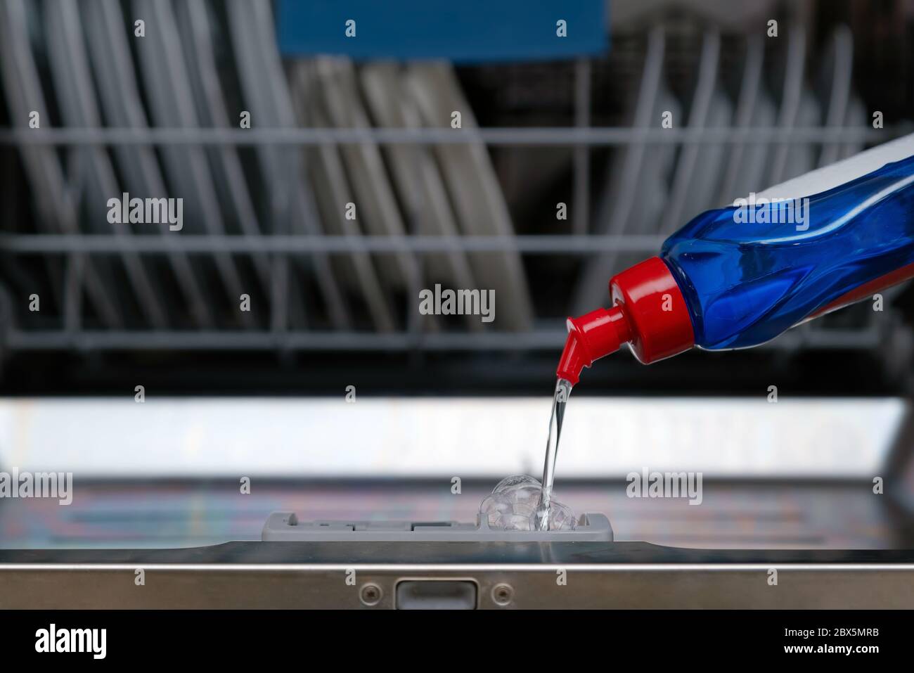 Primo piano di sapone che versa nella lavastoviglie in cucina. Caricamento della lavastoviglie con detergente Foto Stock
