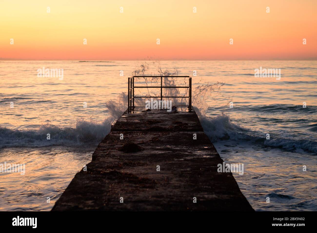 Vecchio molo con le onde al tramonto a Paphos, Cipro Foto Stock