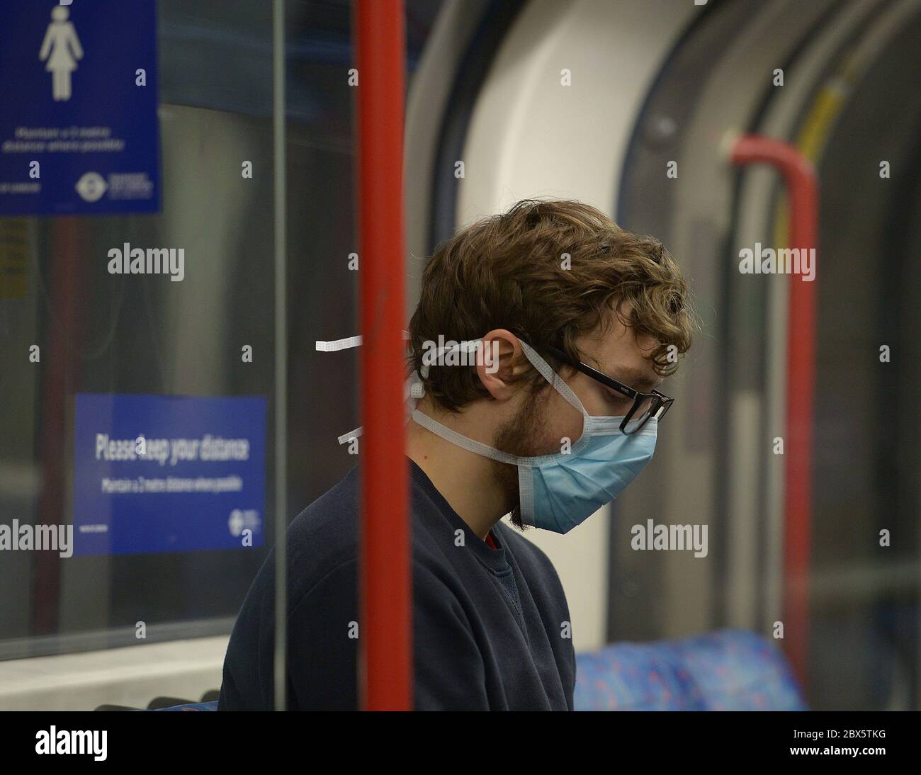 Un passeggero indossa una maschera facciale su un treno sotterraneo della Central Line, dopo l'annuncio che l'uso di una copertura facciale sarà obbligatorio per i passeggeri sui trasporti pubblici in Inghilterra a partire da giugno 15. Foto Stock