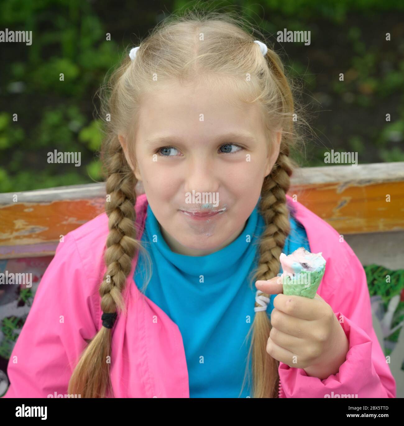 Carina bambina che mangia gelato per strada. Foto Stock