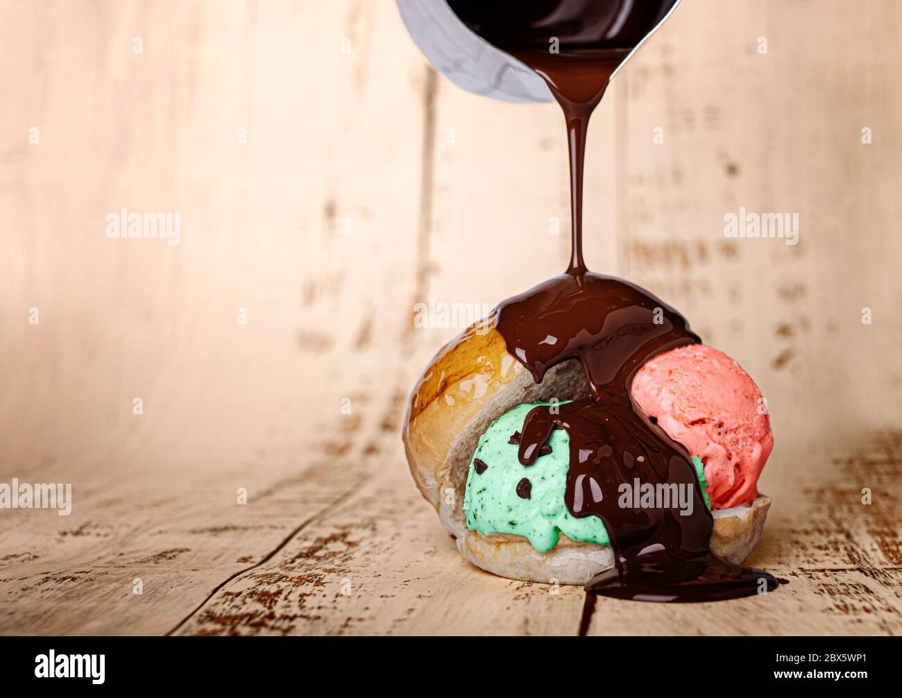 palla di gelato alla fragola e alla menta all'interno di un panino di pane al latte, che gocciola cioccolato liquido Foto Stock
