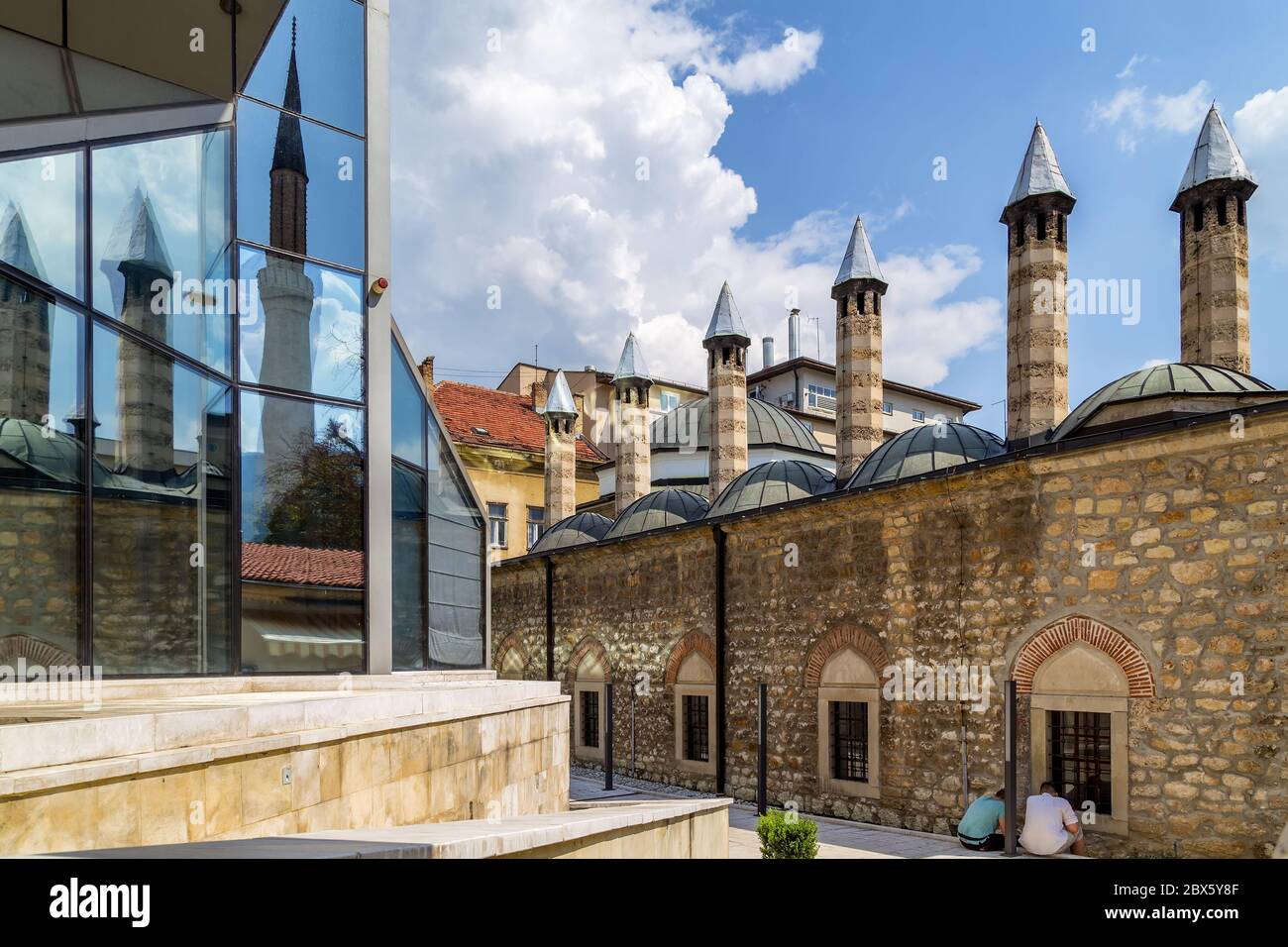 Le torri del Museo Gazi Husrev bey si riflettono nelle finestre di vetro dell'edificio moderno. Sarajevo,centro.Bosnia Erzegovina. Foto Stock