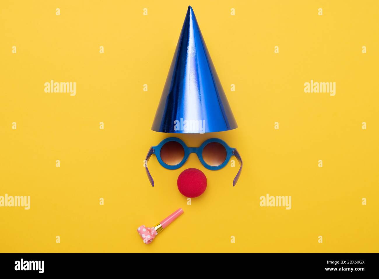 Naso di clown e cappello di partito sulla parete gialla. Concetto di buon compleanno. Foto Stock