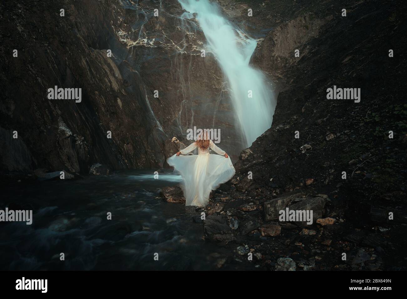 Bella donna e forti cascate di montagna Foto Stock