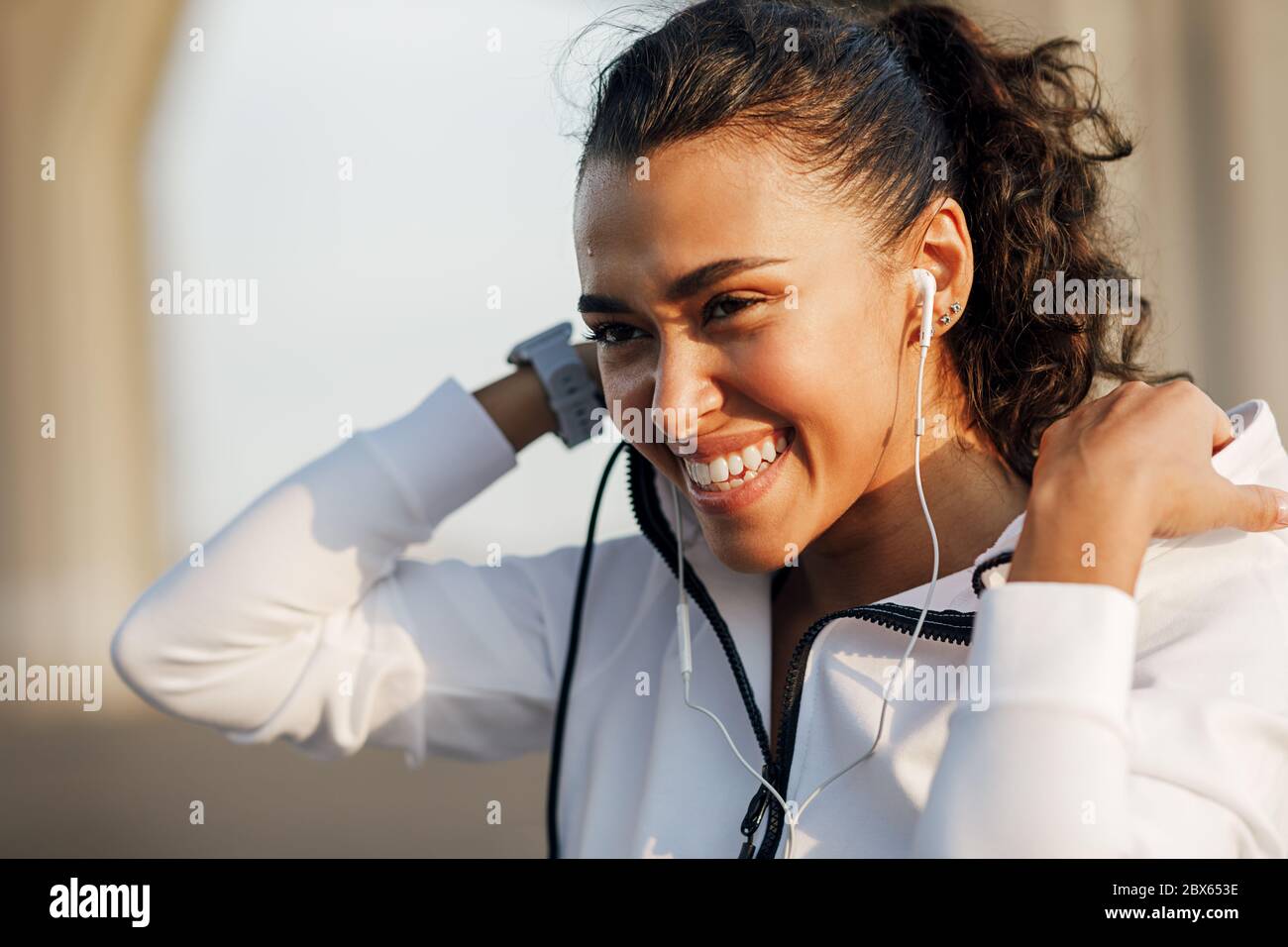 Ritratto di una giovane donna che indossa una felpa con cappuccio e sorride dopo un allenamento Foto Stock