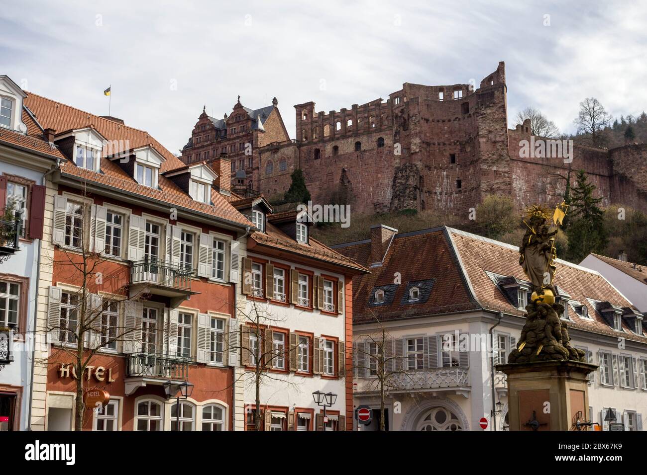 Pittoresco edificio storico nel centro storico di Heidelberg, Germania, con belle rovine del castello sullo sfondo e la statua della peste Foto Stock
