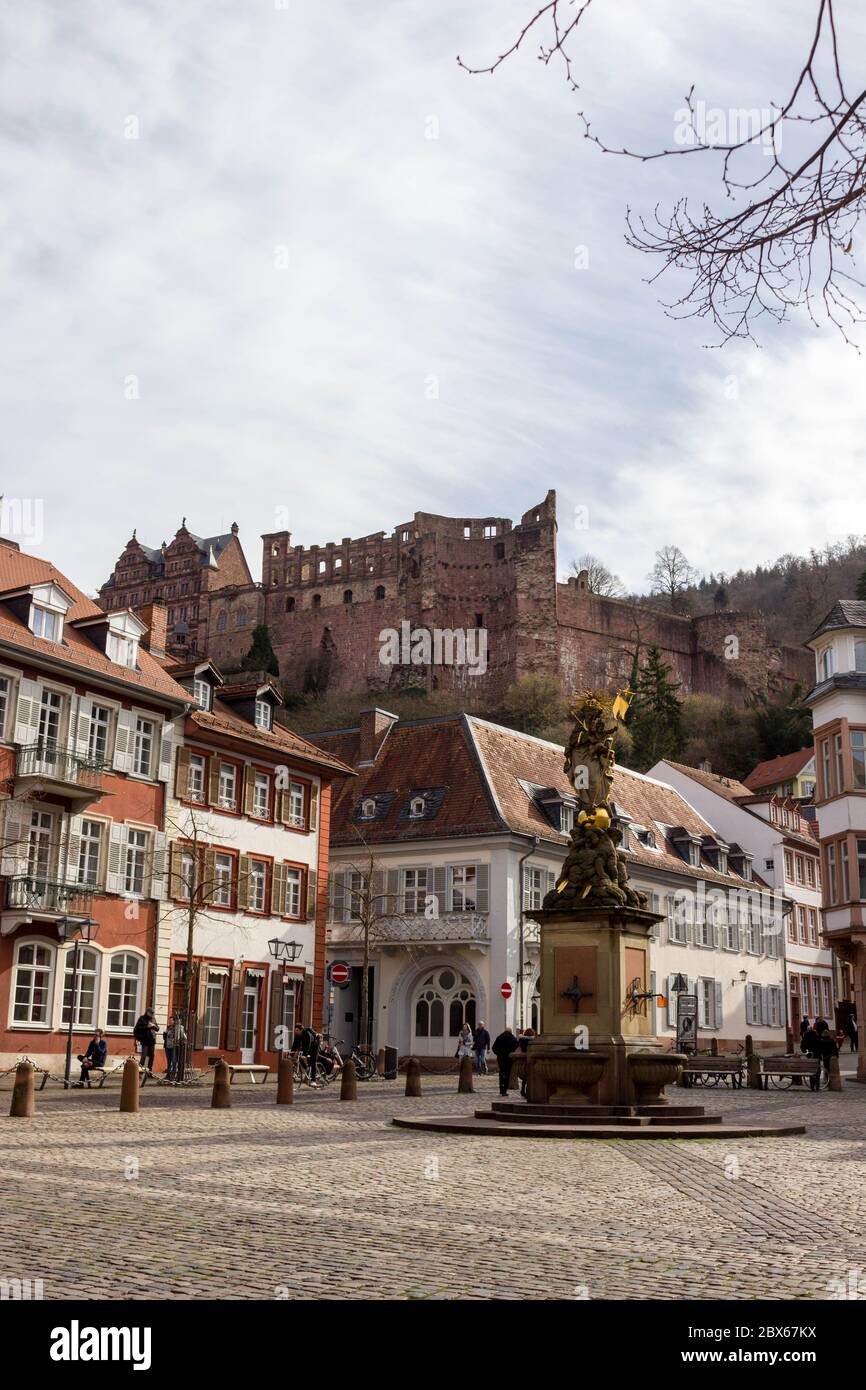 Pittoresco edificio storico nel centro storico di Heidelberg, Germania, con belle rovine del castello sullo sfondo e la statua della peste Foto Stock