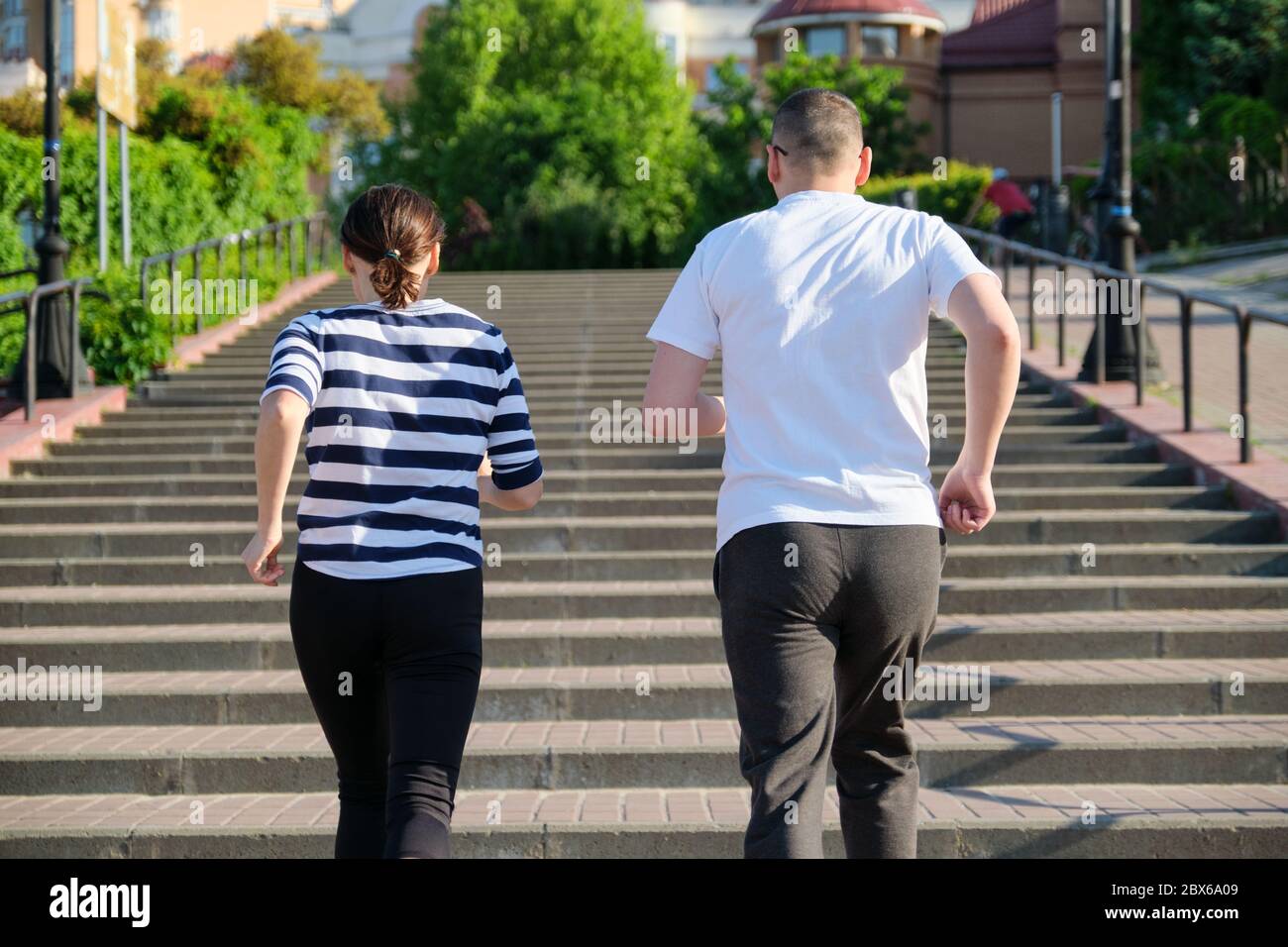 Coppia che corre sulle scale nella vista posteriore della città Foto Stock