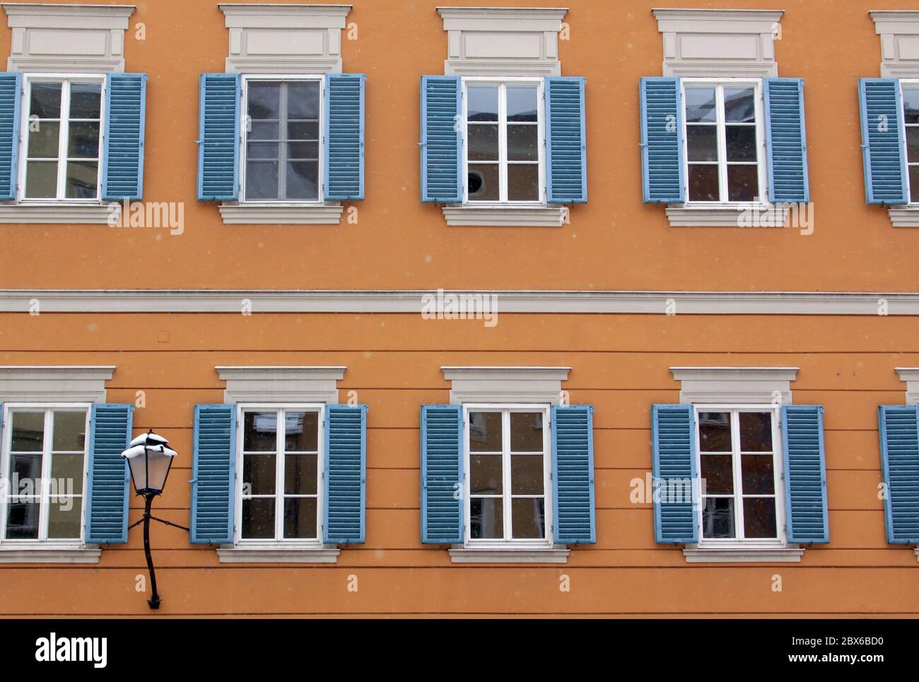 Molte finestre identiche sulla facciata arancione dell'edificio e sulla lampada da strada Foto Stock