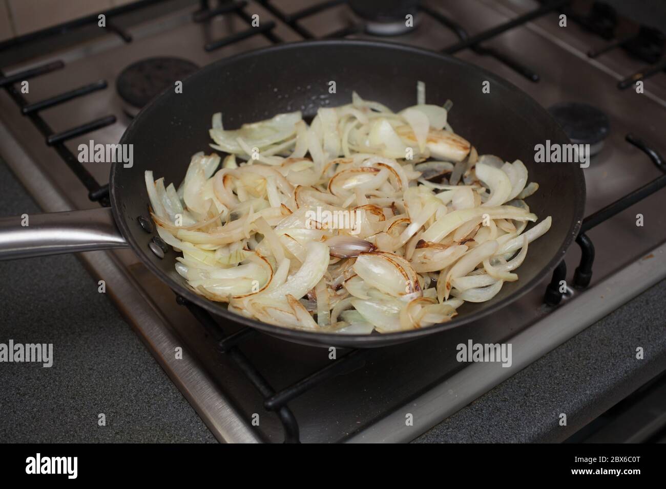 Cipolle brune affette frittura a olio su forno a gas Foto Stock