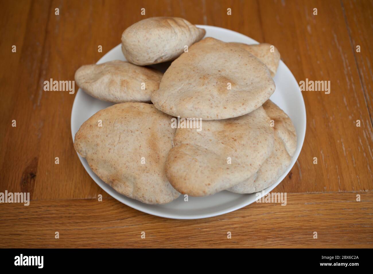 Mezza dozzina di pitta di pane appena sfornate servite su un piatto bianco Foto Stock