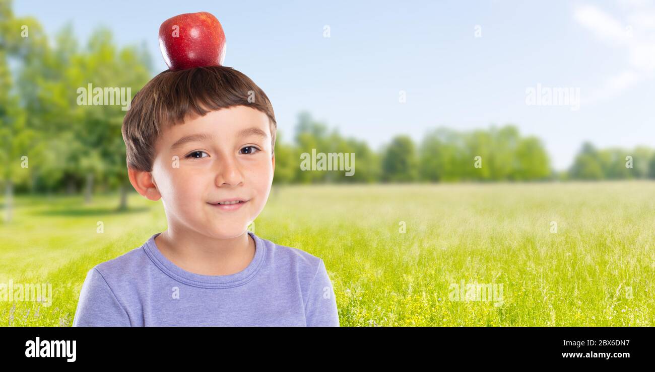 Bambino ragazzo piccolo con mela rossa sulla sua testa all'aperto copyspace copia spazio sano mangiare concetto fuori Foto Stock