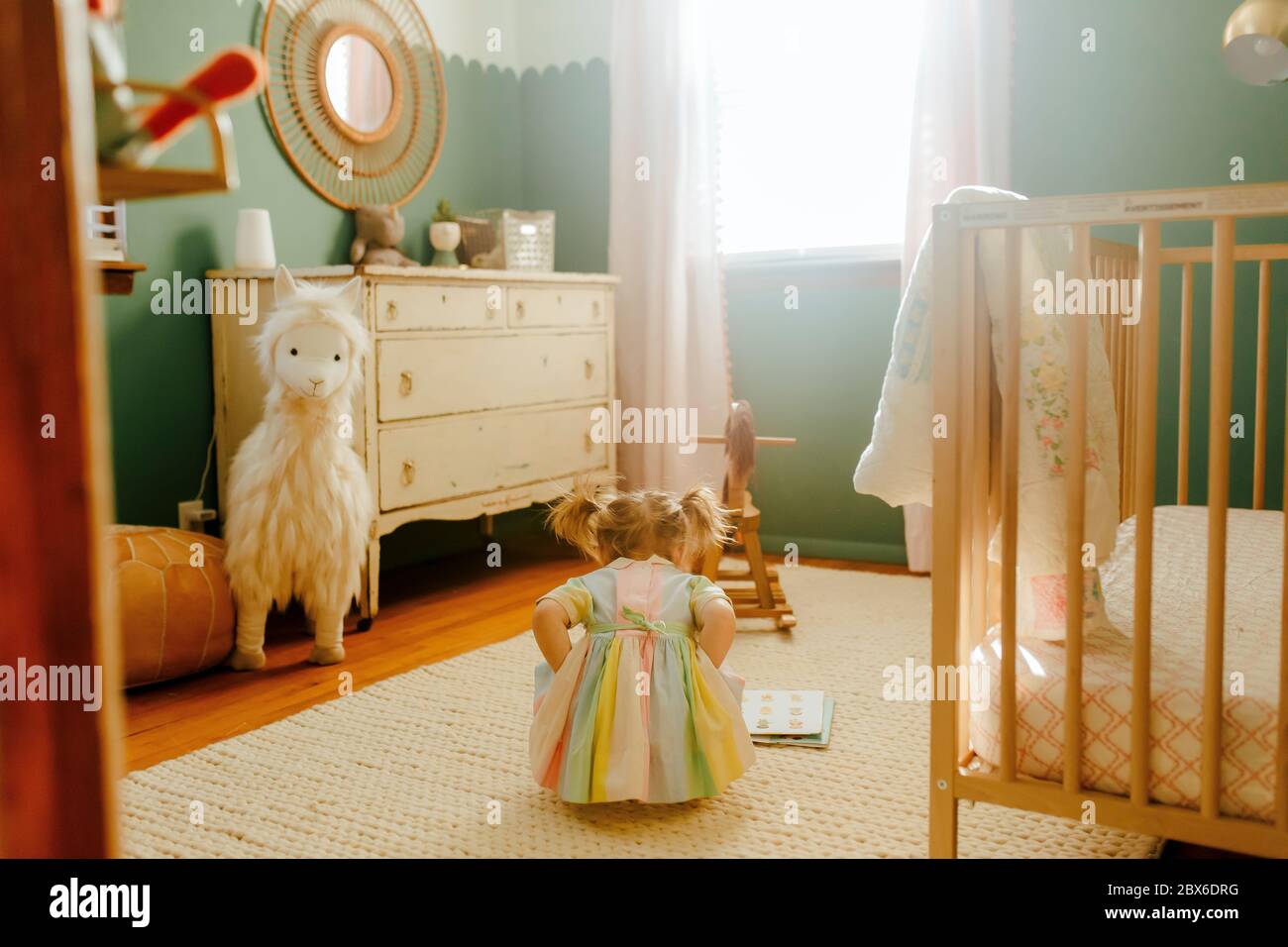 Bambina che legge un libro nella sua stanza Foto Stock