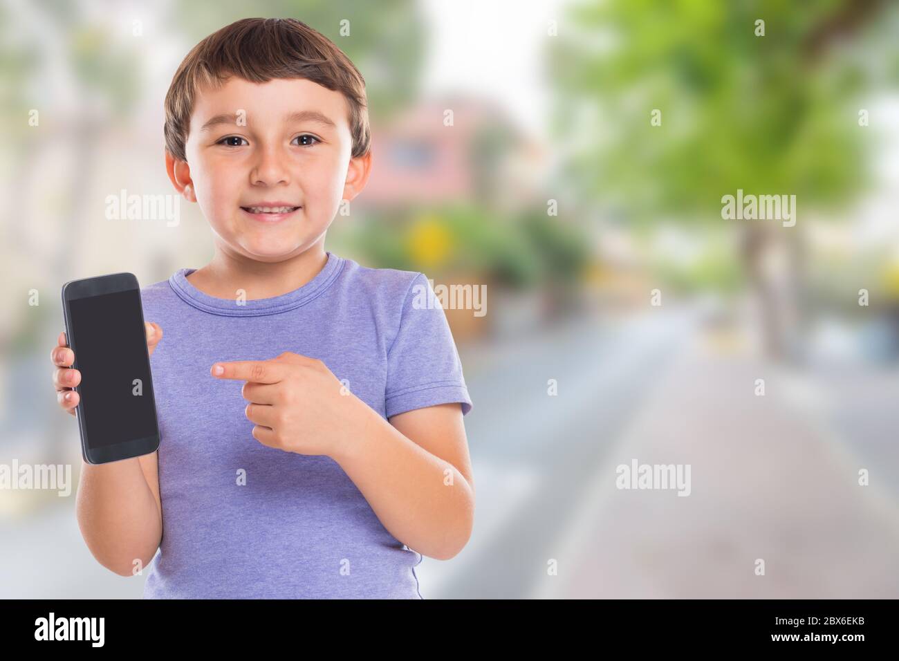 Bambino ragazzo che punta a smartphone cellulare intelligente telefono cellulare città copyspace copia spazio di marketing pubblicità all'aperto Foto Stock