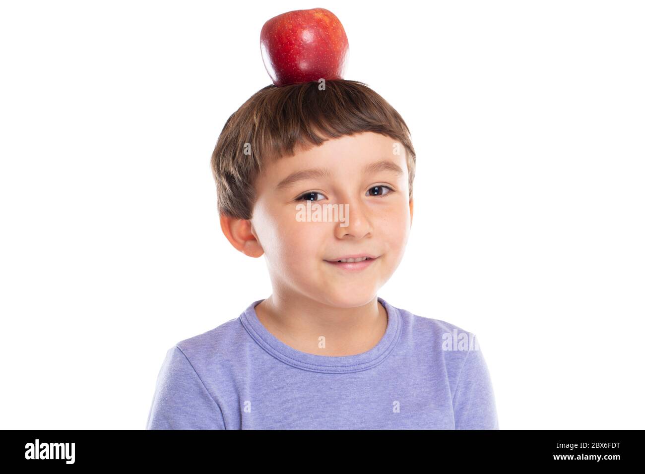 Bambino giovane con mela rossa sulla testa concetto di alimentazione sana isolato su sfondo bianco Foto Stock
