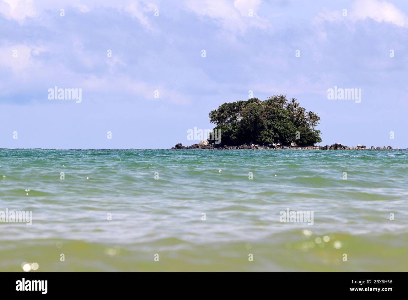 Isola tropicale con palme da cocco in un oceano, vista pittoresca dall'acqua, fuoco selettivo. Coloratissima stagione con cielo blu Foto Stock