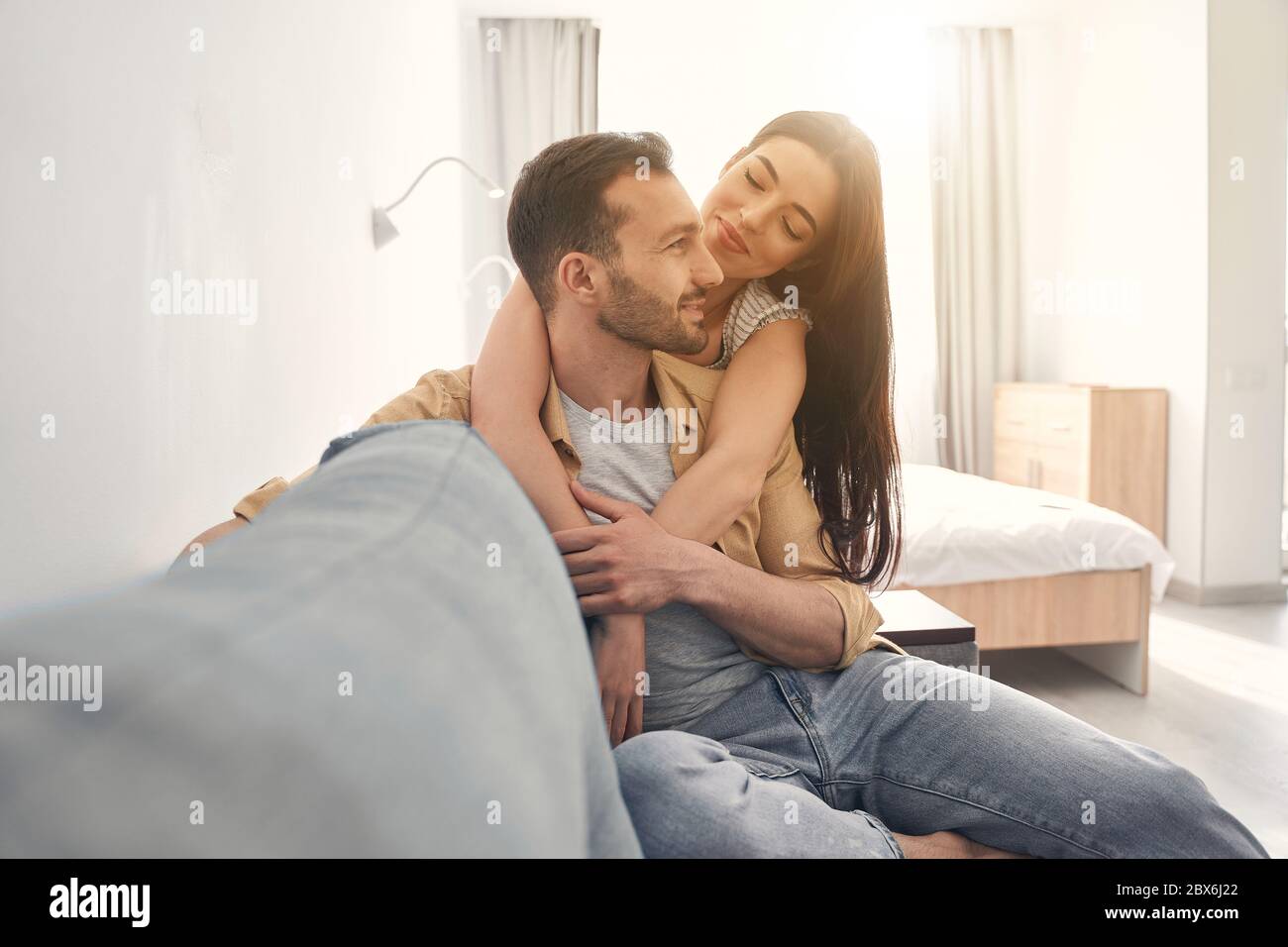 Adorabile coppia amorevole abbracciando su un divano morbido a casa Foto Stock
