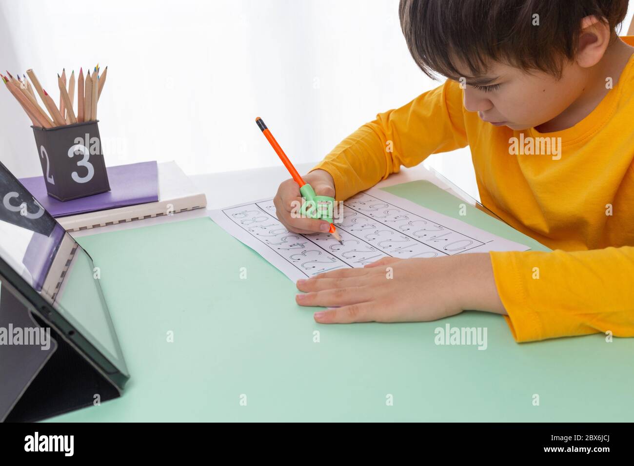 bambino fare compiti, ragazzo uso ergonomico di portamatite di  addestramento, correzione della presa della matita, insegnare ai bambini come  tenere una penna, handwriting esercizi con le dita Foto stock - Alamy