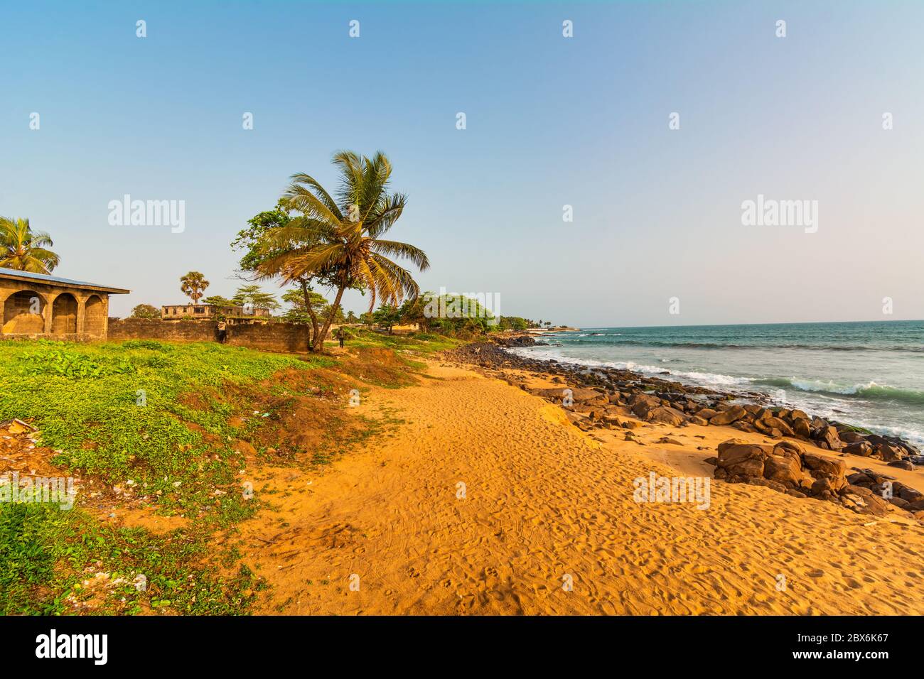 Spiaggia con sabbia rossa e rocce nere con cielo blu a Città del Congo, Monrovia, Liberia Foto Stock