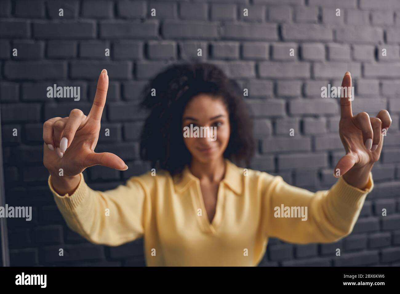 Donna con testa arricciata e messa a fuoco che mostra un gesto della mano Foto Stock
