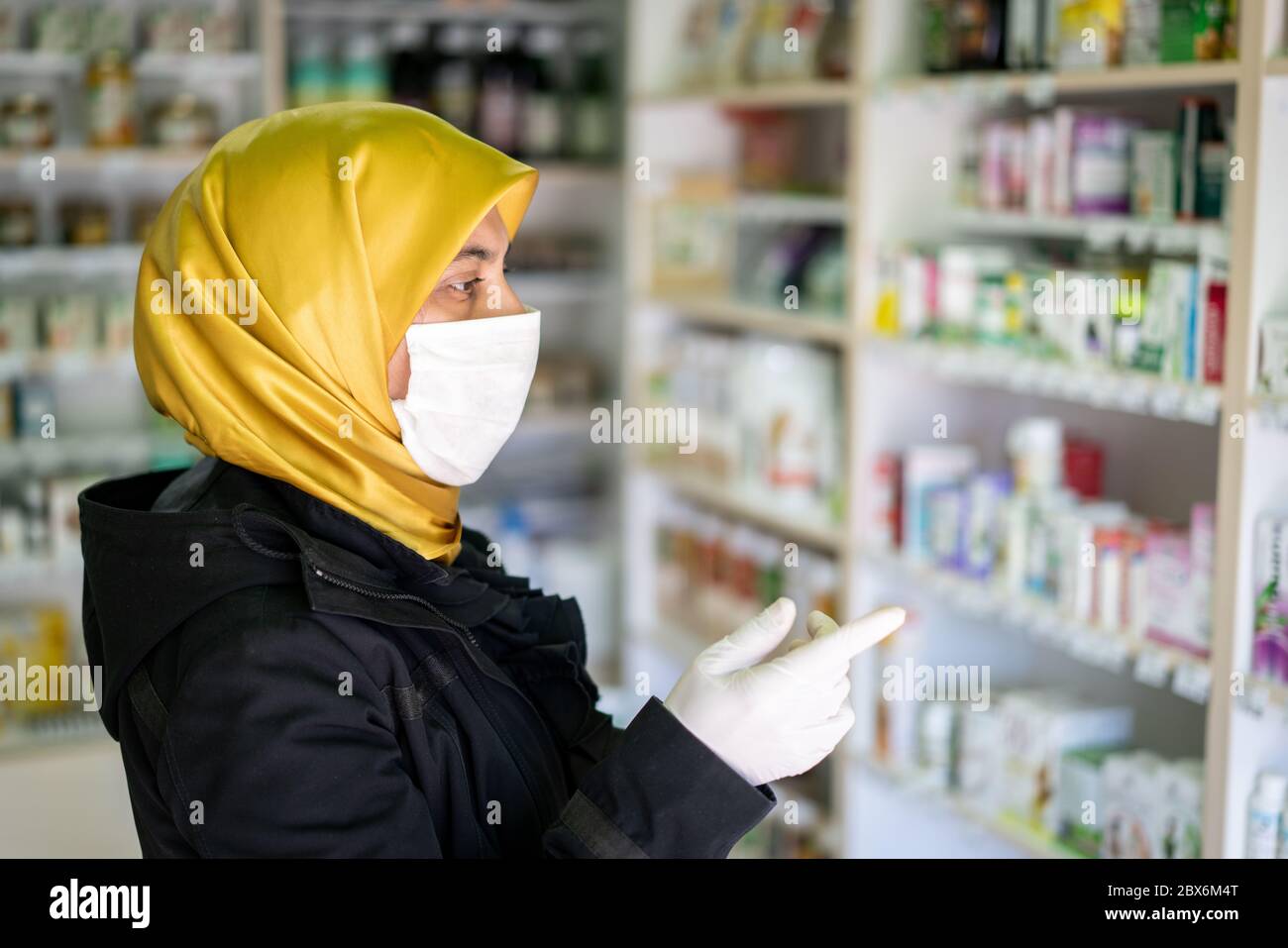 Donna mediorientale in farmacia scegliendo la medicina Foto Stock