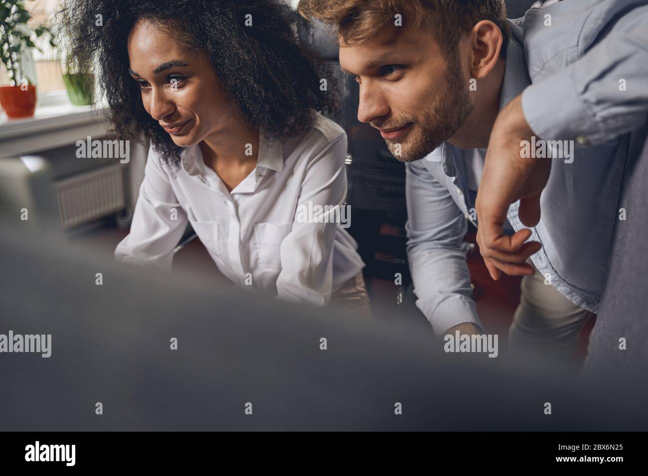 Donna sorridente con testa riccia e il suo collega soddisfatto Foto Stock