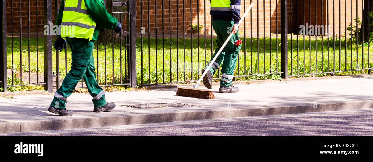 I pulitori di strada a Londra in abbigliamento da lavoro camminano lungo la strada Foto Stock