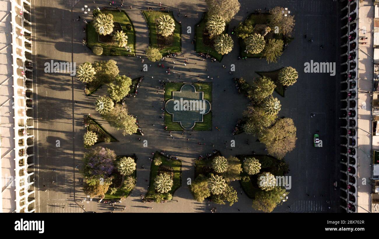 Vista dall'alto e ravvicinata del parco geometrico della piazza principale di Arequipa con archi sui lati. Tramonto - ombre di alberi e persone Foto Stock