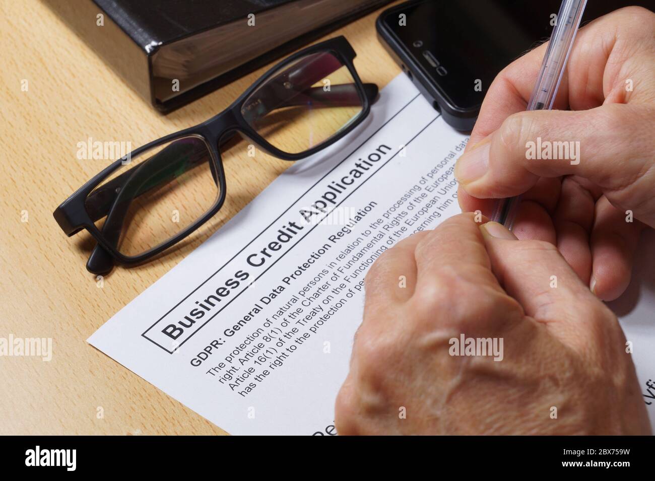 Domanda di credito aziendale. Un uomo compila un modulo di credito con una clausola GDPR (General Data Protection Regulation). Foto Stock