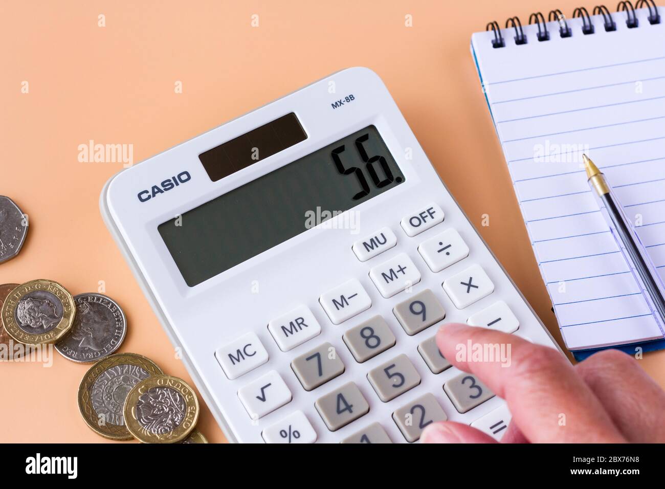 Una calcolatrice e alcune monete britanniche. Concetto di budget per le famiglie. Foto Stock