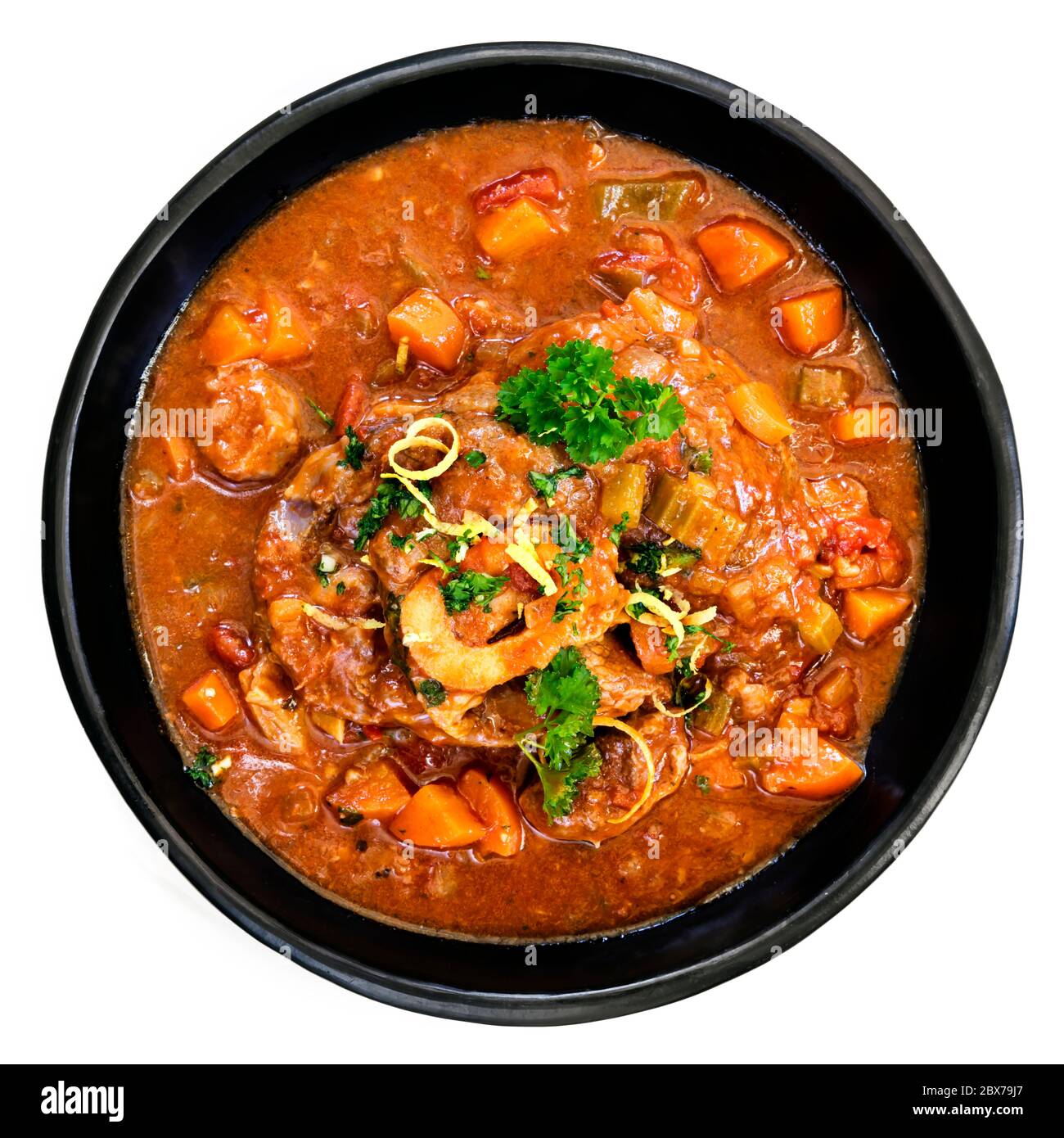 Osso buco vitello canks casseruola in rustico piatto nero. Vista dall'alto, isolata su bianco. Foto Stock
