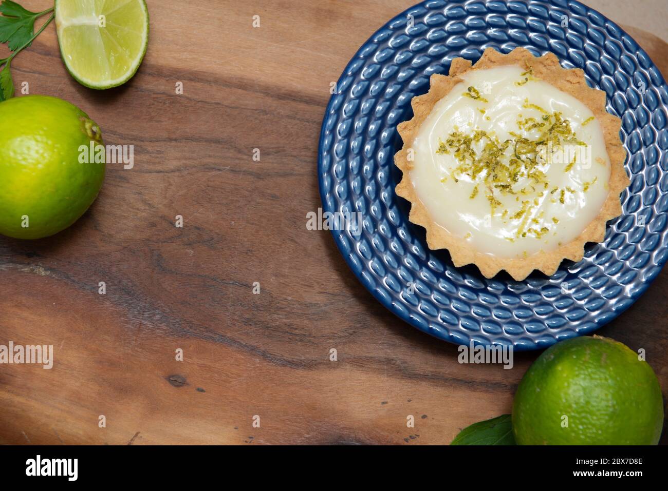 Vista dall'alto della tradizionale torta francese al limone su legno. Vista delle sezioni del limone dall'alto. Tartlet su piatto blu d'annata e fette di limone su tavola di legno. Foto Stock