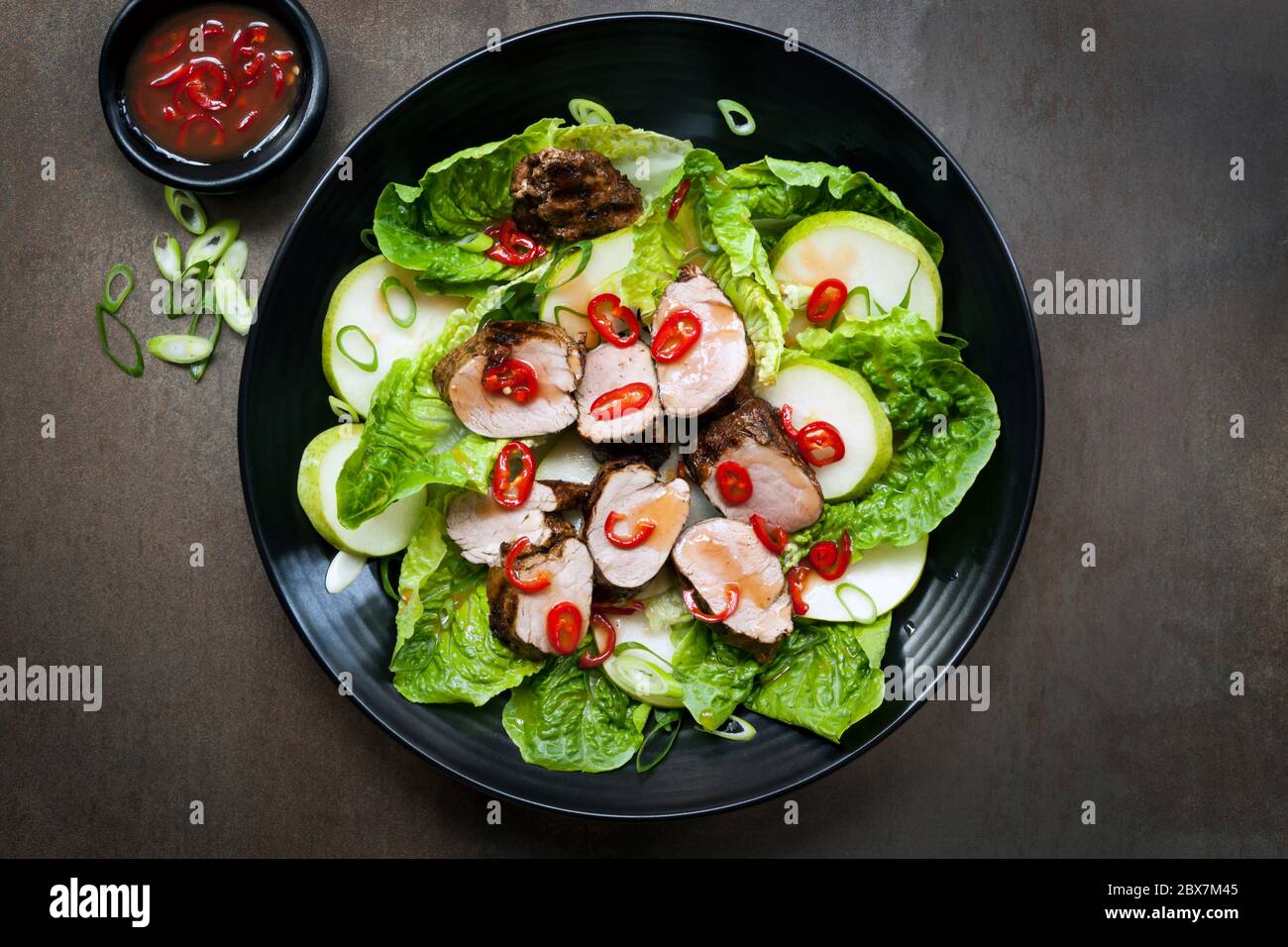 Insalata di maiale con peperoncino, pera e lattuga. Filetto grigliato marinato in salsa di prugne. Foto Stock