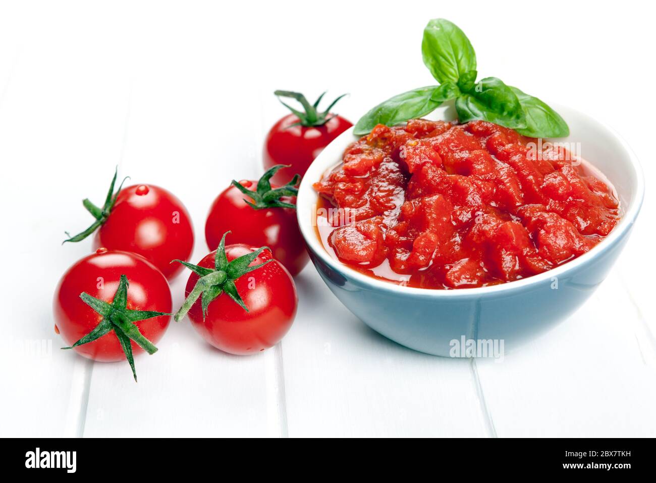 Pomodori a dadini e interi, guarniti con basilico. Foto Stock