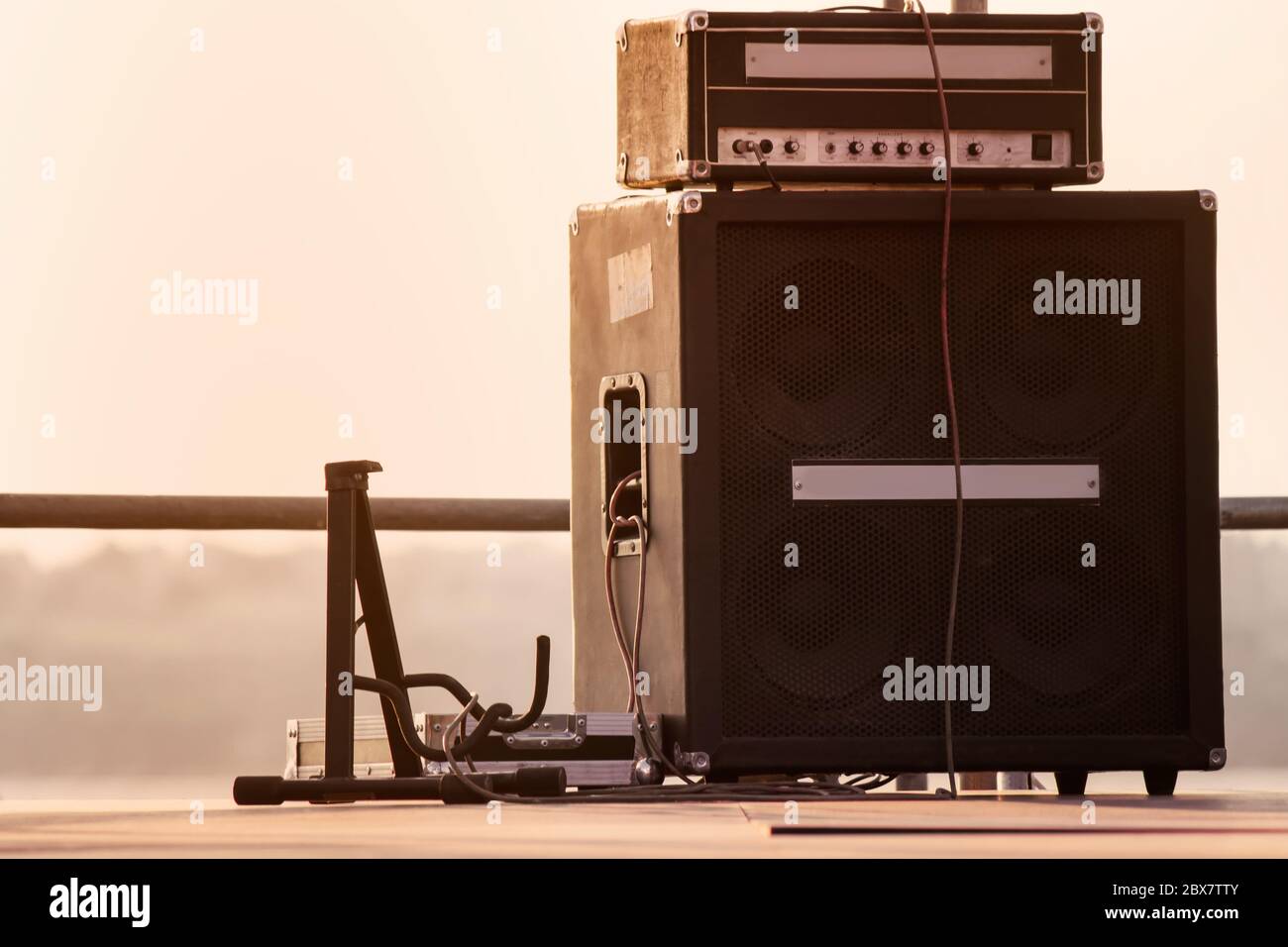 Supporto per chitarra con sistema di amplificazione in piedi sul palco all'aperto serale. Foto Stock