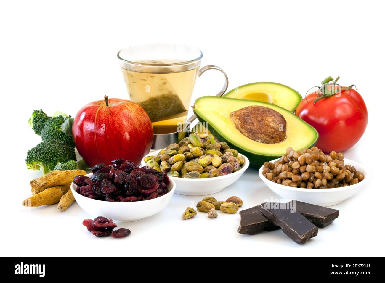 Varietà di alimenti ricchi di antiossidanti, isolati su bianco. Comprende broccoli, mela, tè verde, pistacchi, mirtilli rossi, avocado, pomodori, lenticchie e. Foto Stock