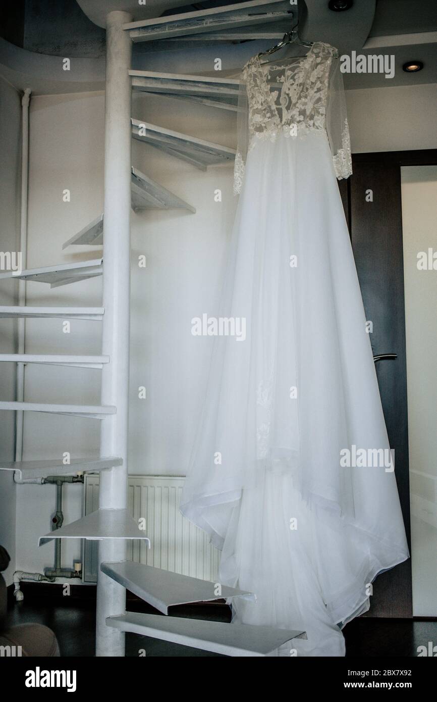 Abito da sposa su appendiabiti sulle scale nella camera sposa. Giorno di nozze. Foto Stock