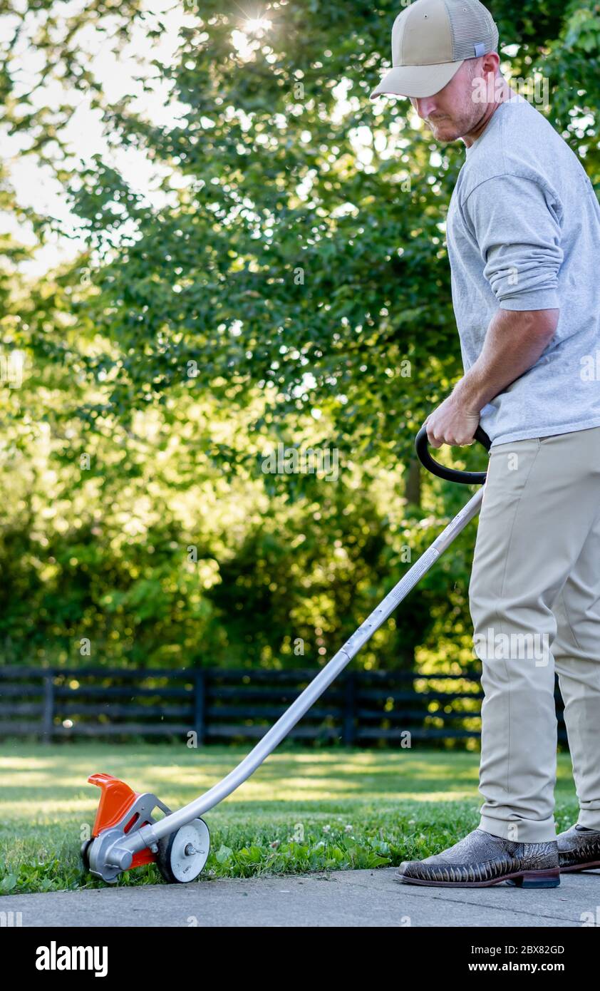 Uomo caucasico che usa un rasaerba/trimmer in Kentucky Foto Stock