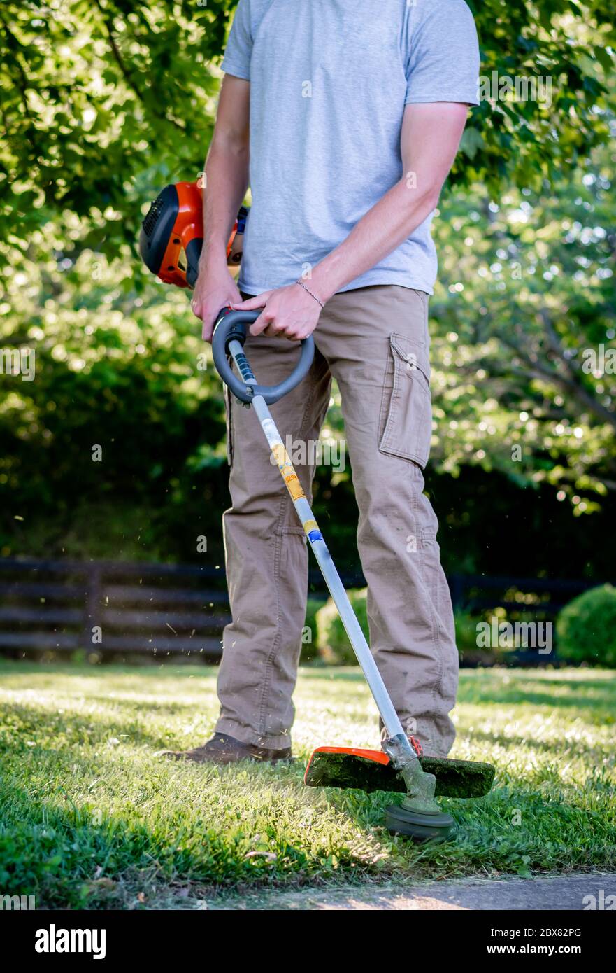 Uomo caucasico che usa un rasaerba/trimmer in Kentucky Foto Stock