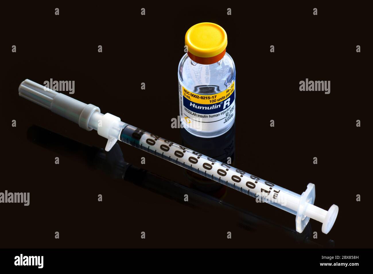 Portland, O marzo 15 2020. Un flaconcino di Humulin R Insulin, un farmaco essenziale per il diabete, con una siringa da 1 ml di insulina su fondo nero riflettente Foto Stock