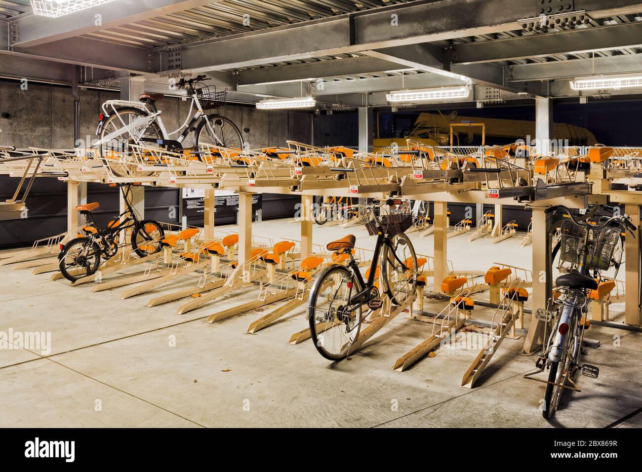 Parcheggio autonomo per biciclette a più livelli nella città giapponese di Tokyo di notte, con la maggior parte delle scaffalature ancora vuote. Foto Stock