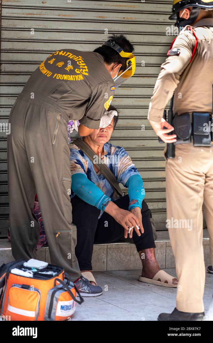 Paramedica e polizia che aiuta signora dopo un incidente durante la pandemia di Covid, Bangkok, Thailandia Foto Stock