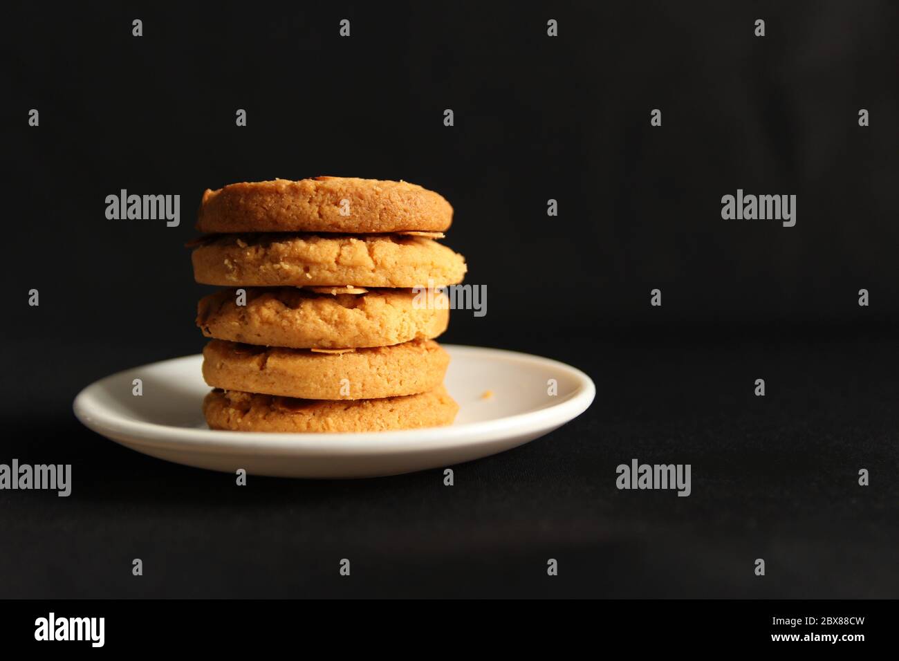 Biscotti alle mandorle in un piatto bianco. Foto isolata su spazio copia nero Foto Stock