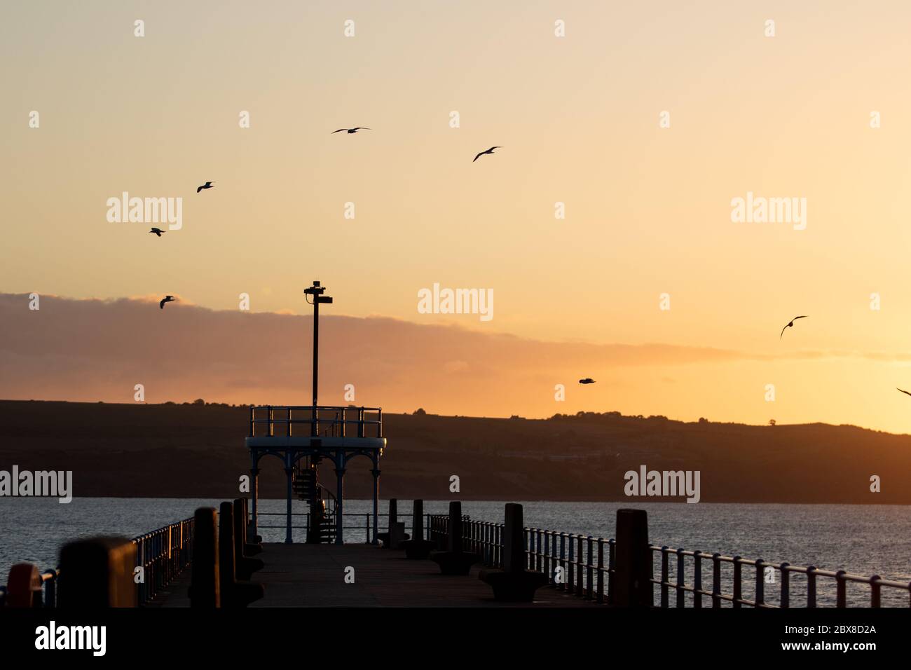 Weymouth, Regno Unito. 6 Giugno 2020. L'alba della mattina presto si innalora sullo Stone Pier a Weymouth Bay. Foto Stock